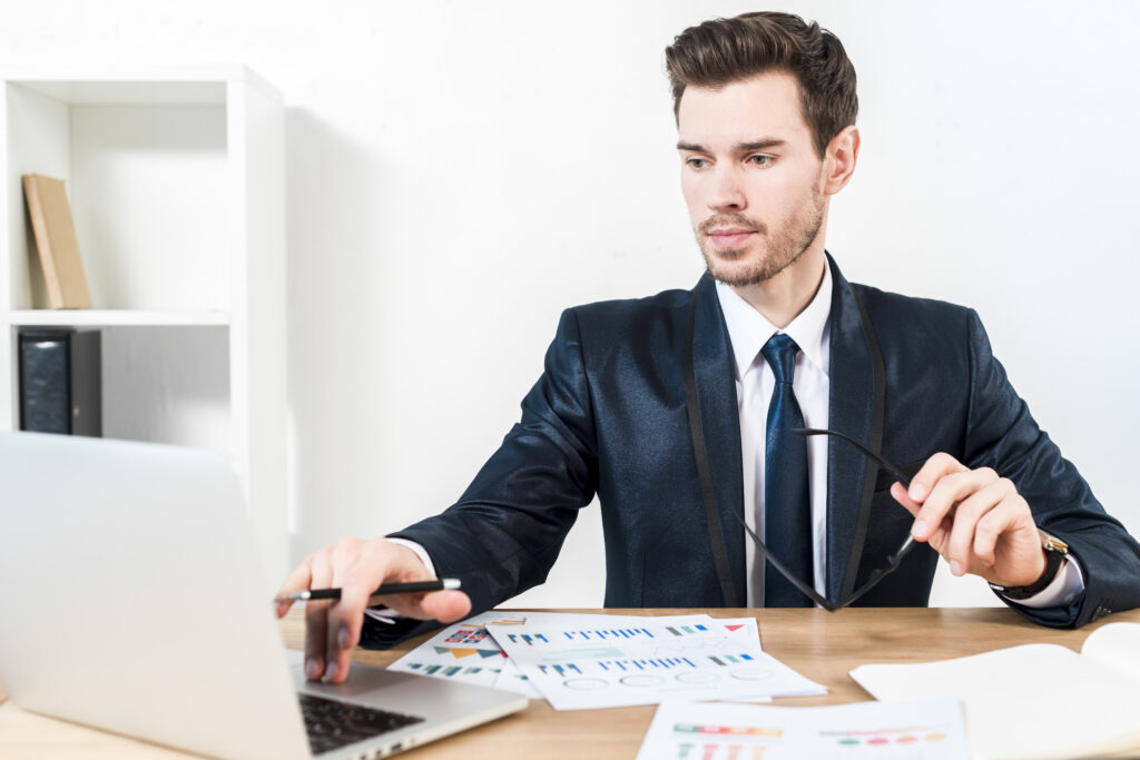 young-confident-businessman-using-laptop-workplace as he is the remote accounting staff